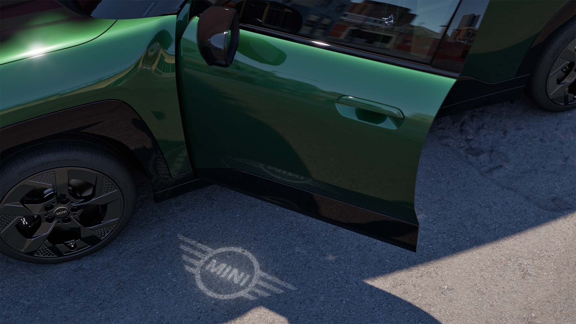 Aussenansicht des vollelektrischen MINI Aceman mit geöffneter Tür und Begrüssungslicht mit MINI Logo auf dem Boden